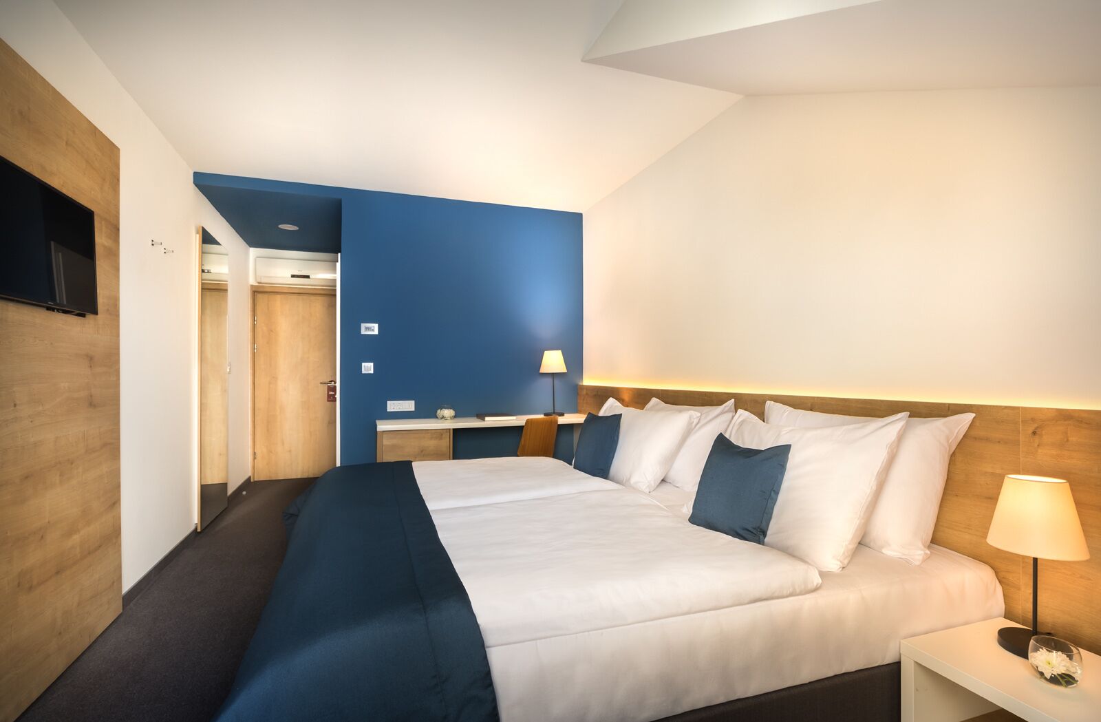 Une chambre d’hôtel avec un grand lit, un bureau et un téléviseur fixé au mur.