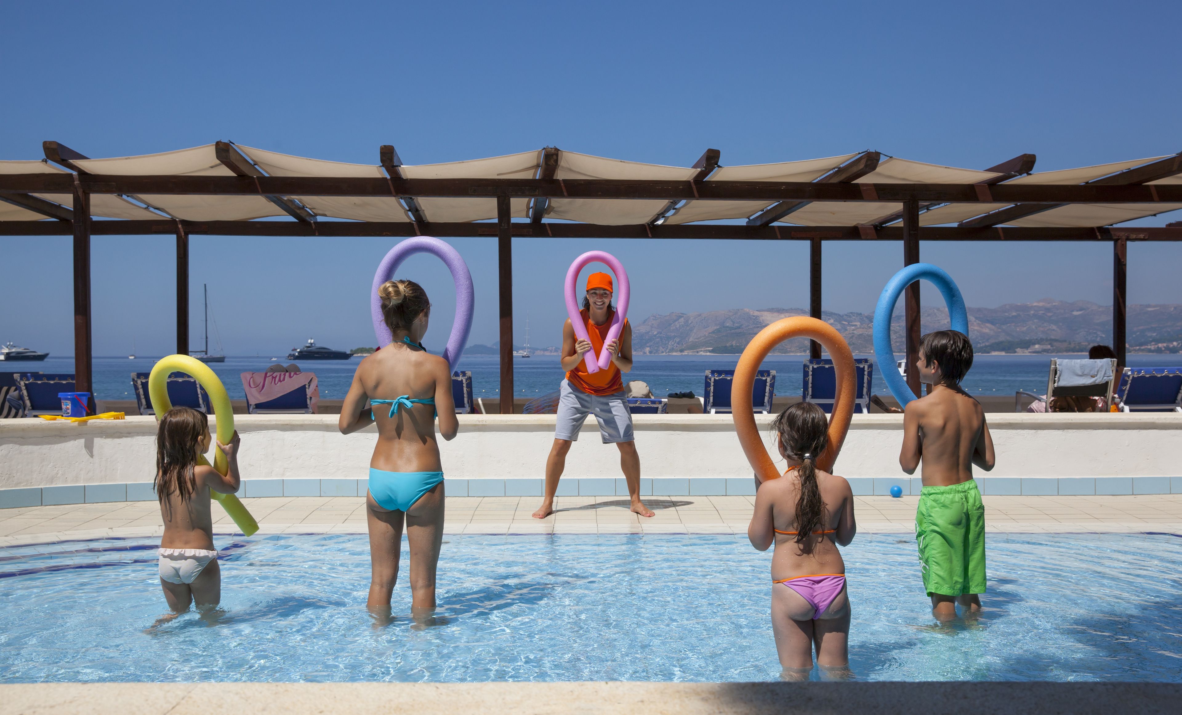 A pool area with a clear view of the sea and boats in the background.