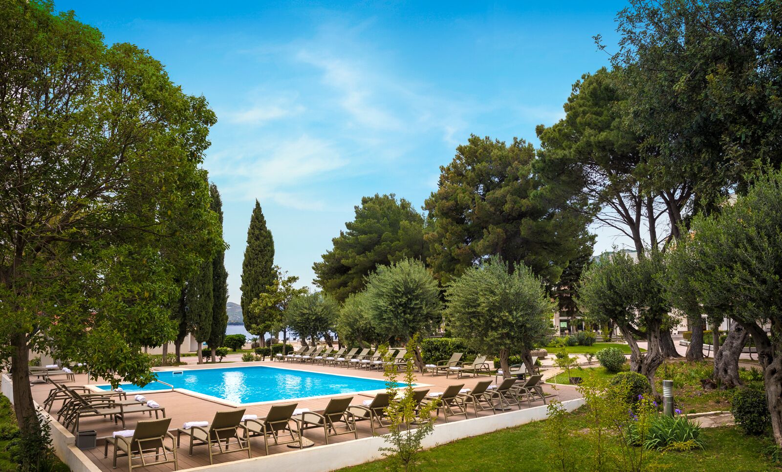 A pool area with lounge chairs and trees.