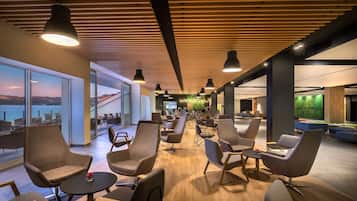 A modern lounge area with seating, a view of the sea, and a green wall feature.