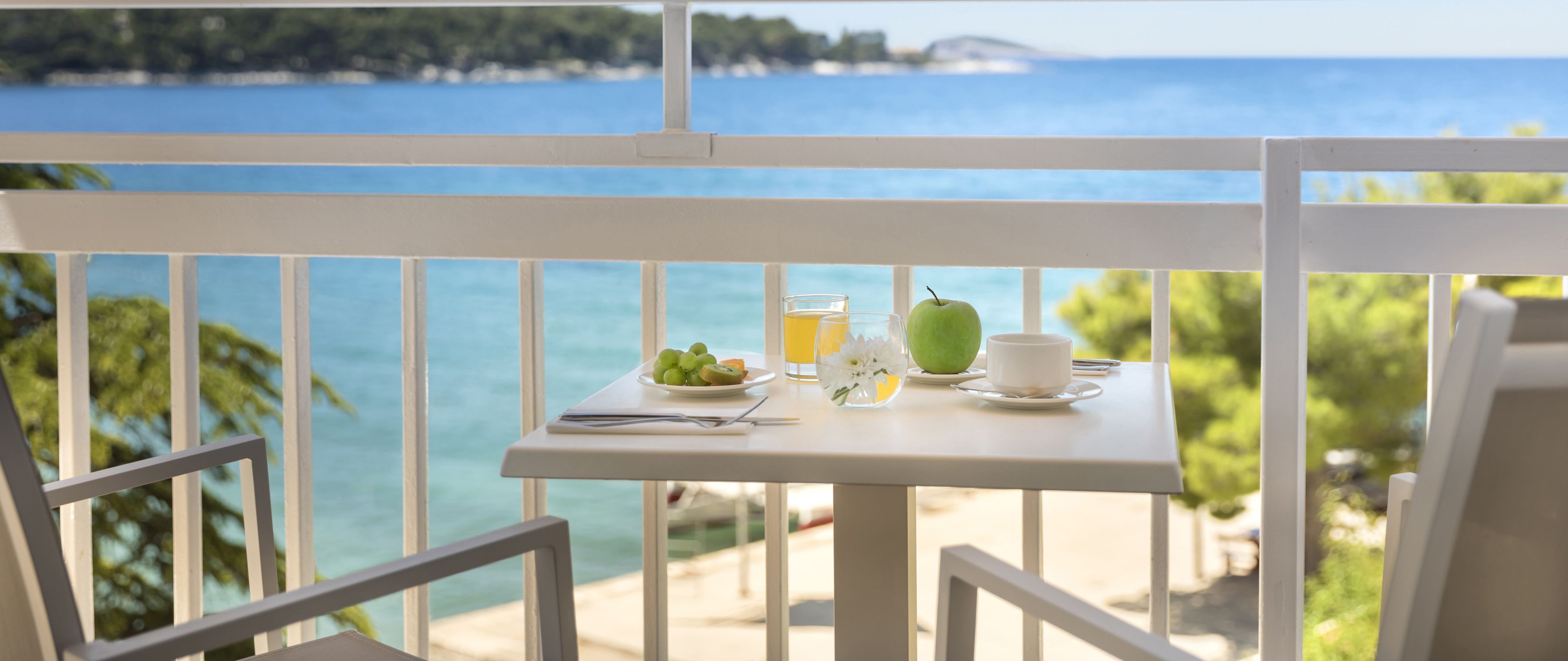 Ein Balkon mit Frühstückstisch und Blick auf die Küste.