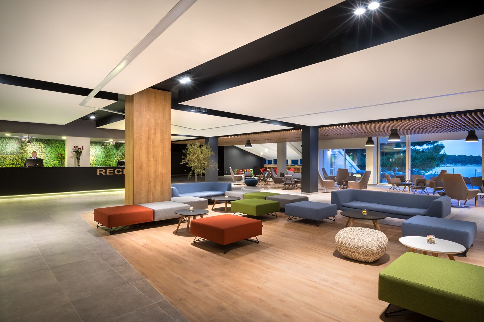 Een moderne lobby met een receptiebalie, zithoeken en grote ramen met uitzicht.