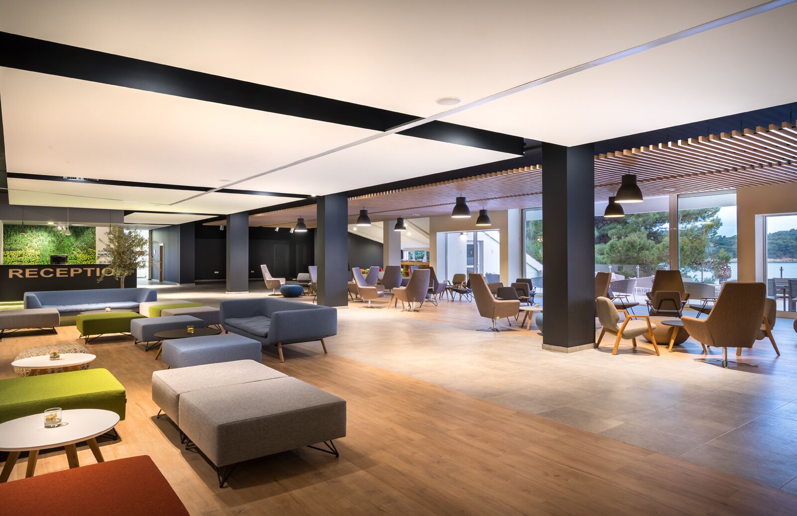 A spacious lobby with a reception area, multiple seating arrangements, and large windows offering views of the outdoors.