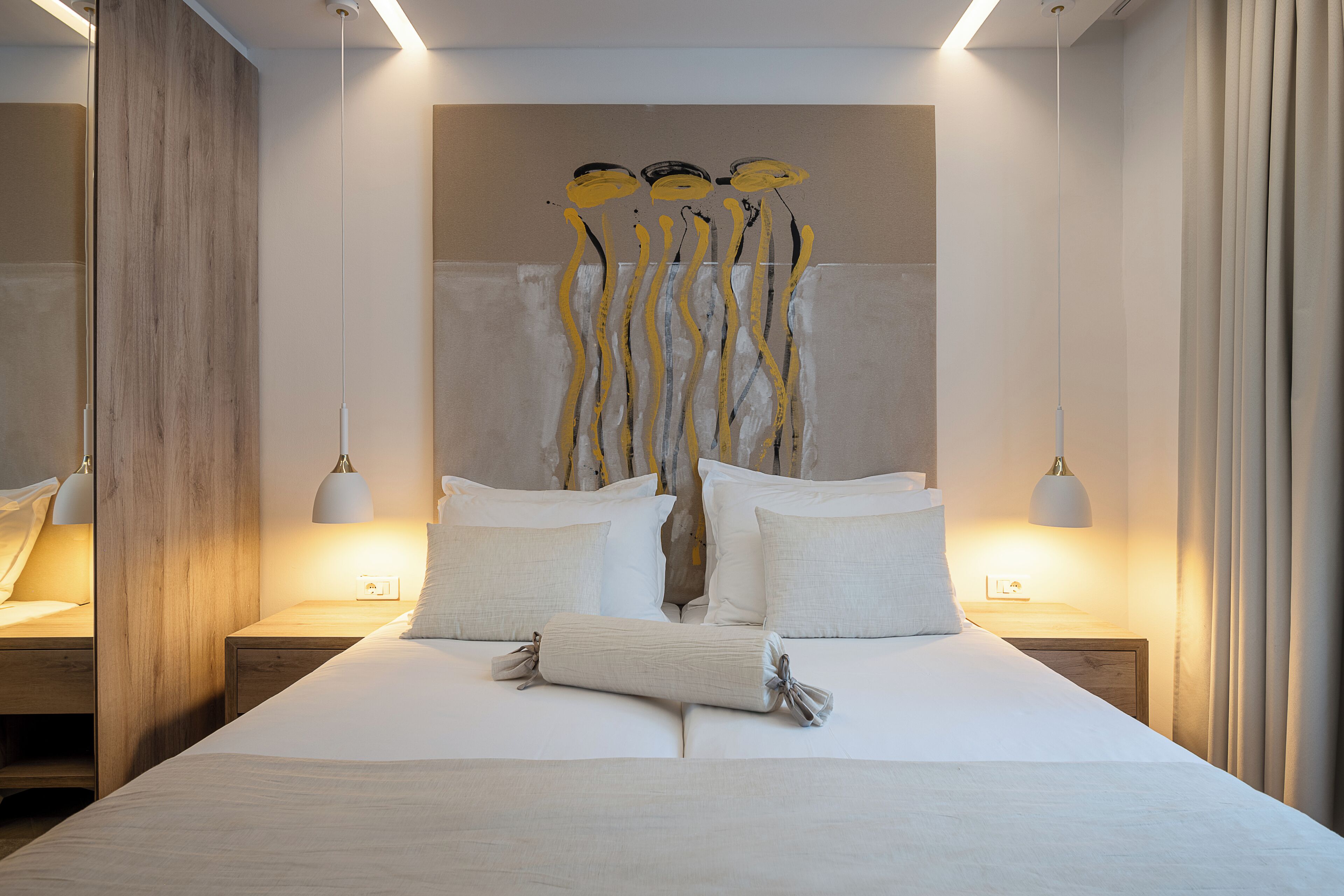 A modern bedroom with a large bed, two bedside tables, and a wall-mounted artwork.