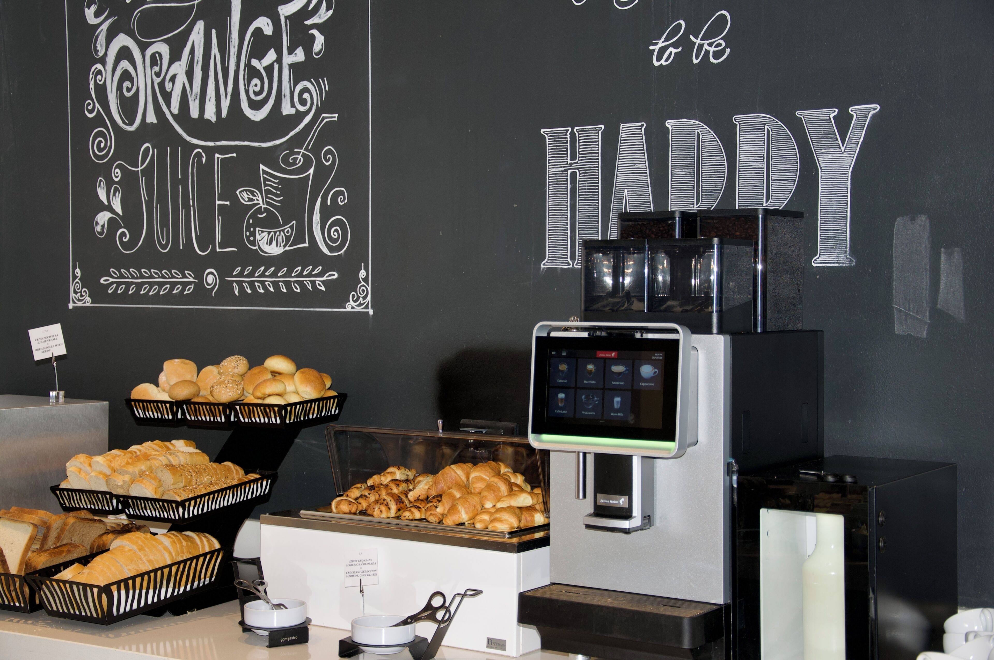 A breakfast buffet with bread, pastries, and a coffee machine.