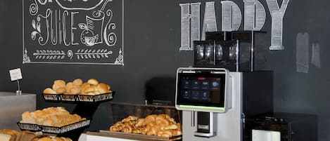A breakfast buffet with bread, pastries, and a coffee machine.