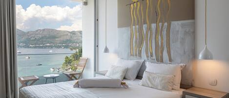 Habitación de hotel con una cama grande, vista al mar y un cuadro en la pared.