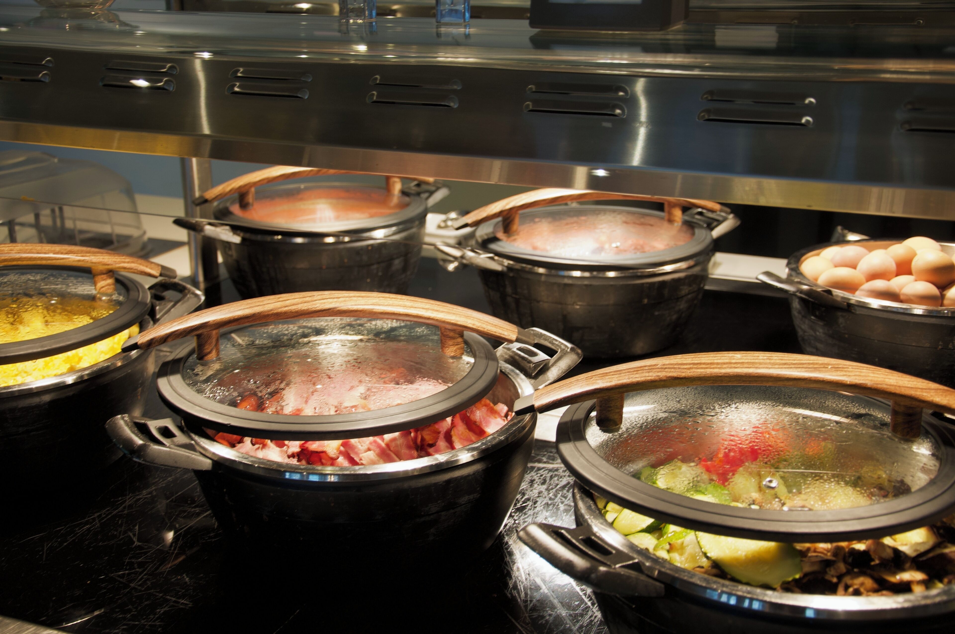 Un buffet proposant divers plats servis dans des récipients couverts.