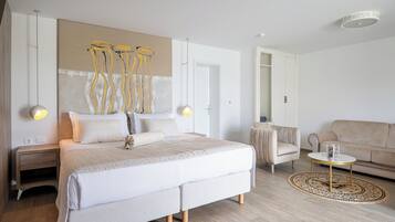 Un dormitorio moderno con una cama grande, mesitas de noche, un sofá y una mesa de centro.