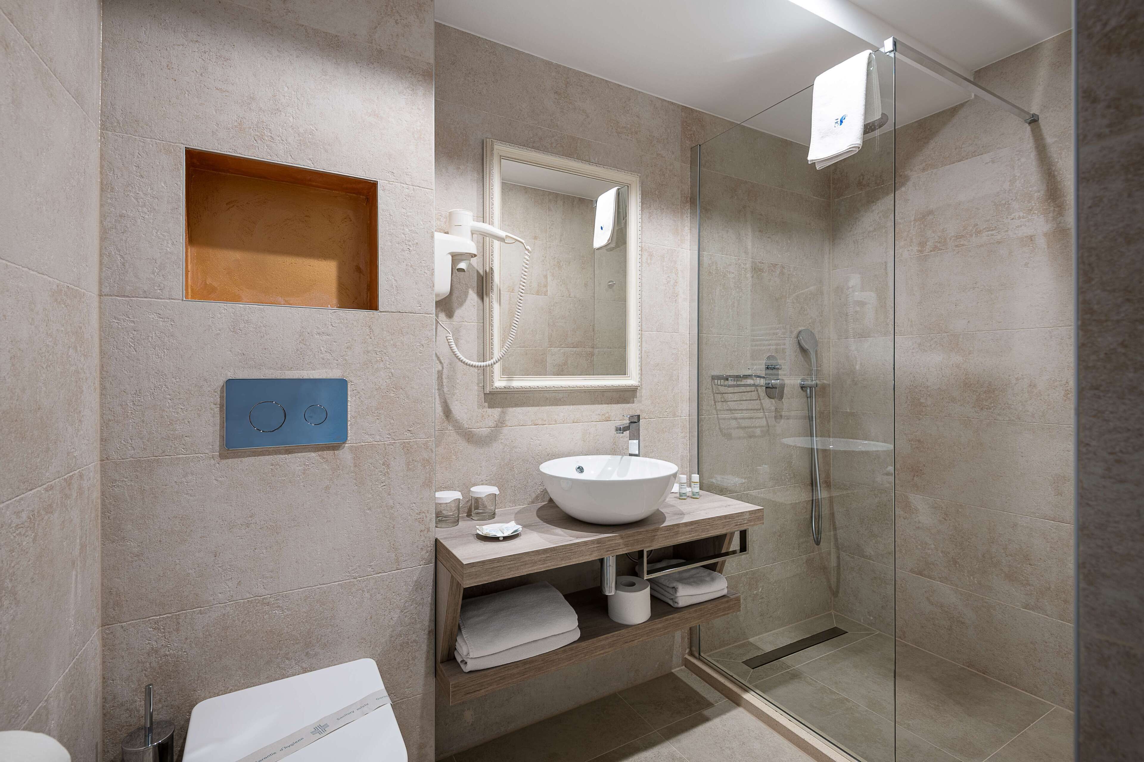 Un baño moderno con ducha de vidrio, un lavamanos blanco y un espejo encima.