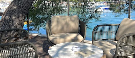 A deck with wicker furniture, a round table, and a view of a marina with boats.