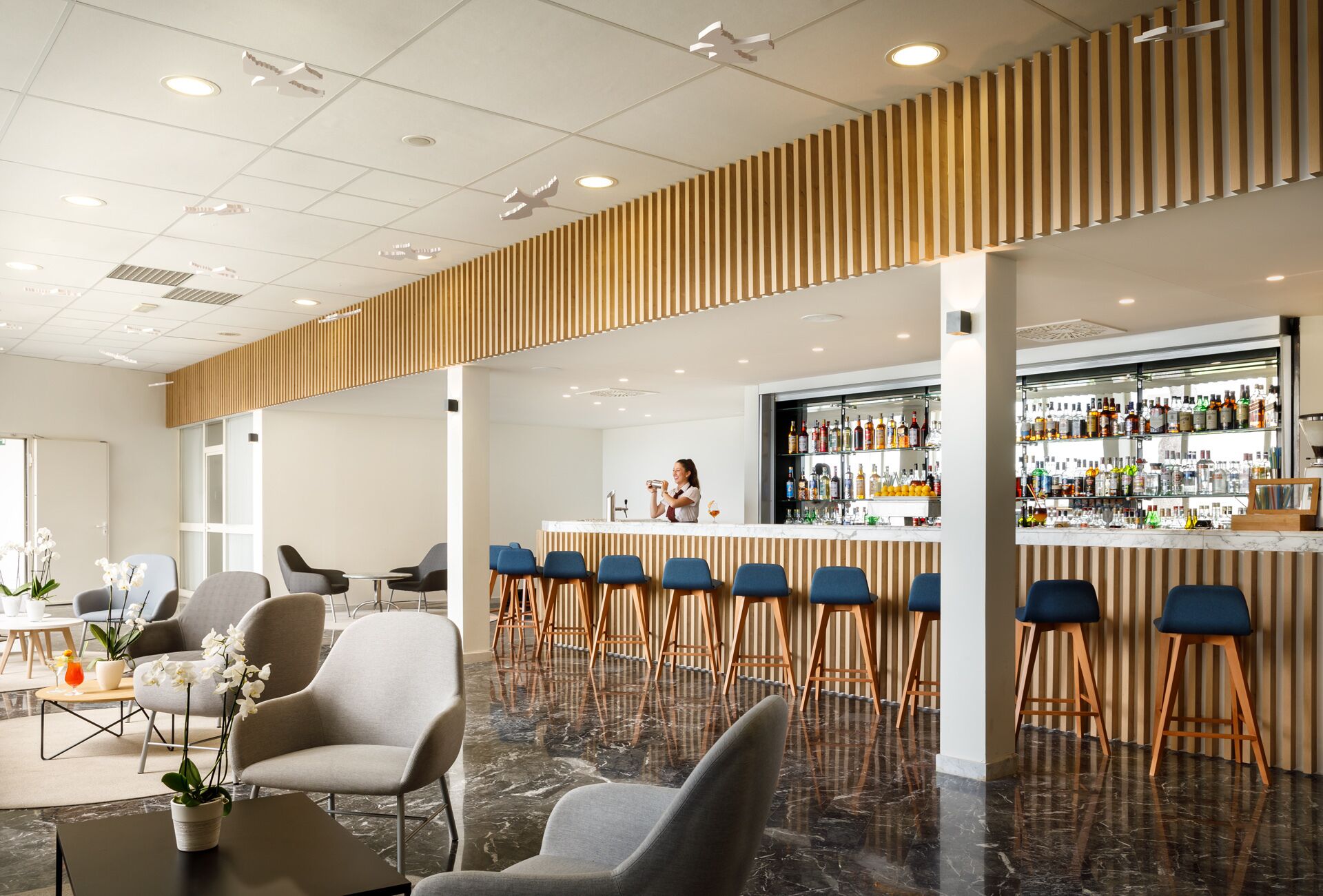 Un espace bar moderne comprenant un comptoir, des sièges et une variété de bouteilles.