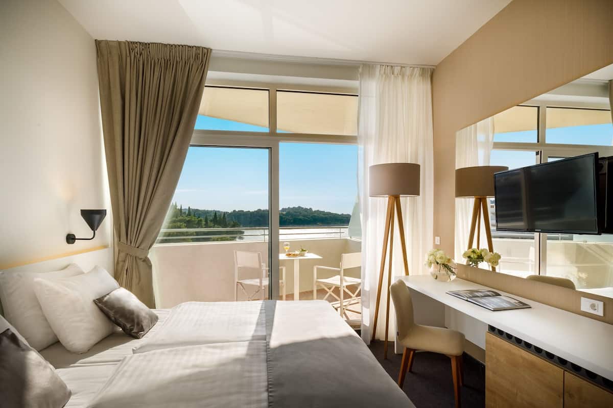 Ein Hotelzimmer mit einem Bett, einem Schreibtisch, einem Fernseher und Blick ins Freie.