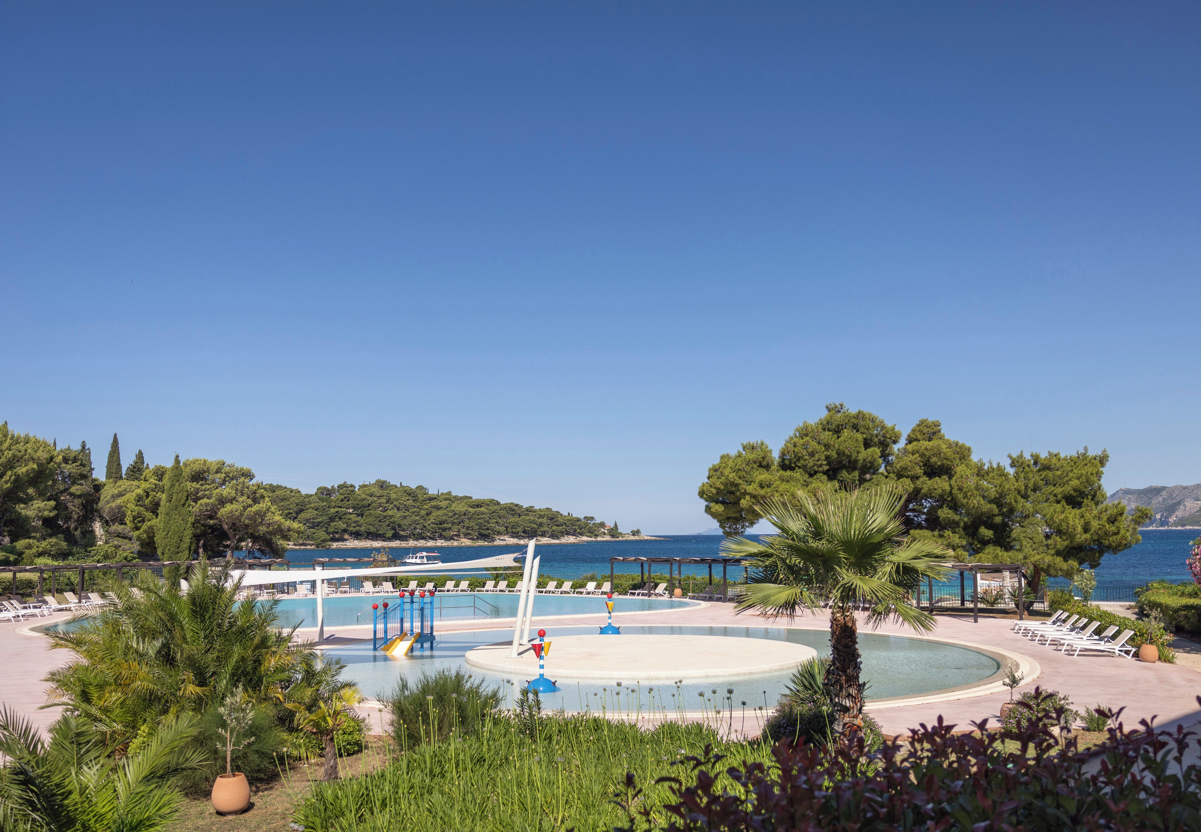 Uma área de piscina com espreguiçadeiras e vista para o mar.