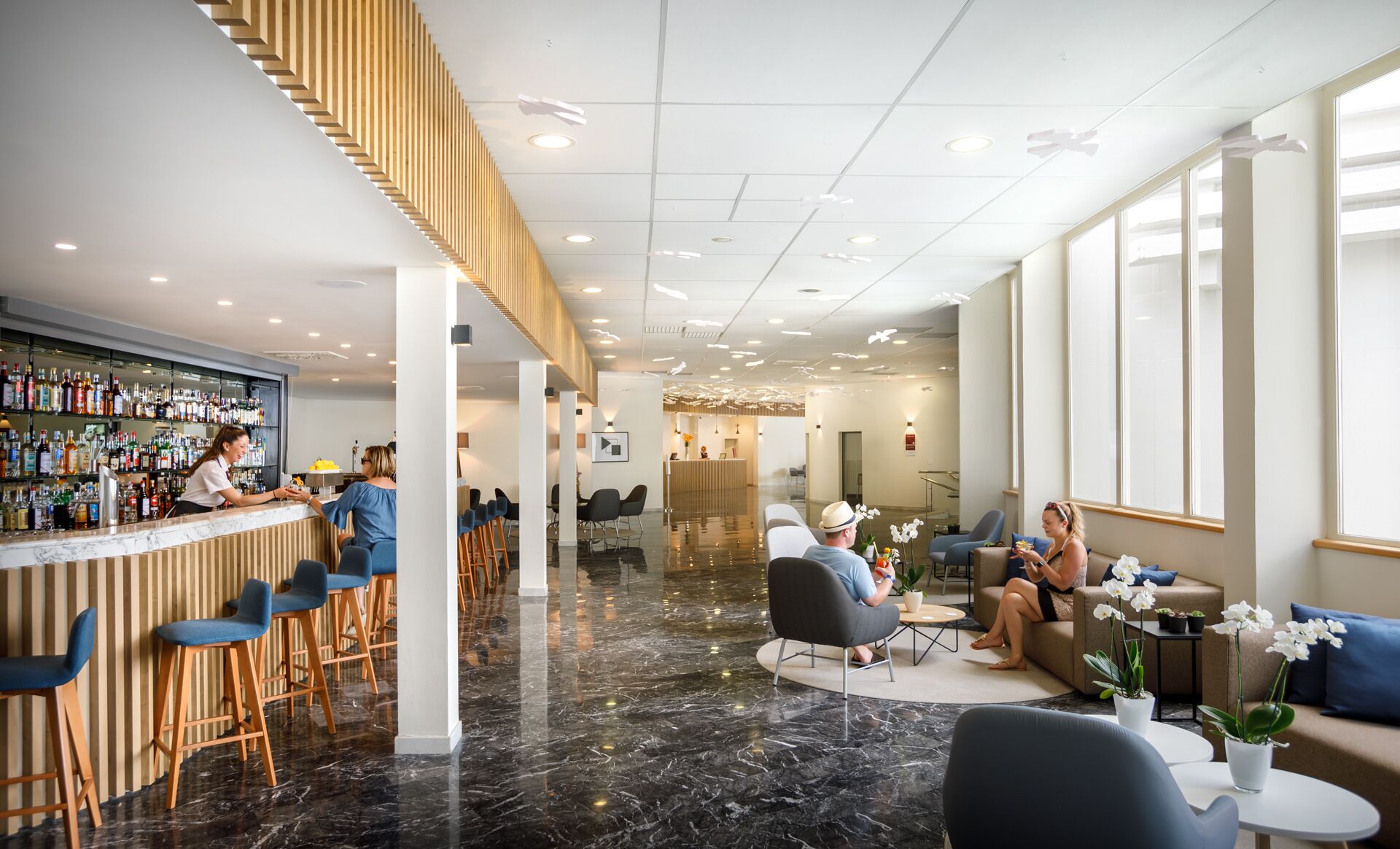 En modern hotellobby med en bardisk, sittplatser och en receptionsdisk.