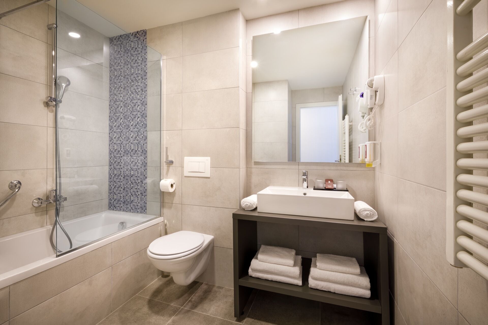 Un baño moderno con cabina de ducha de vidrio, inodoro blanco, tocador con espejo y toallero.