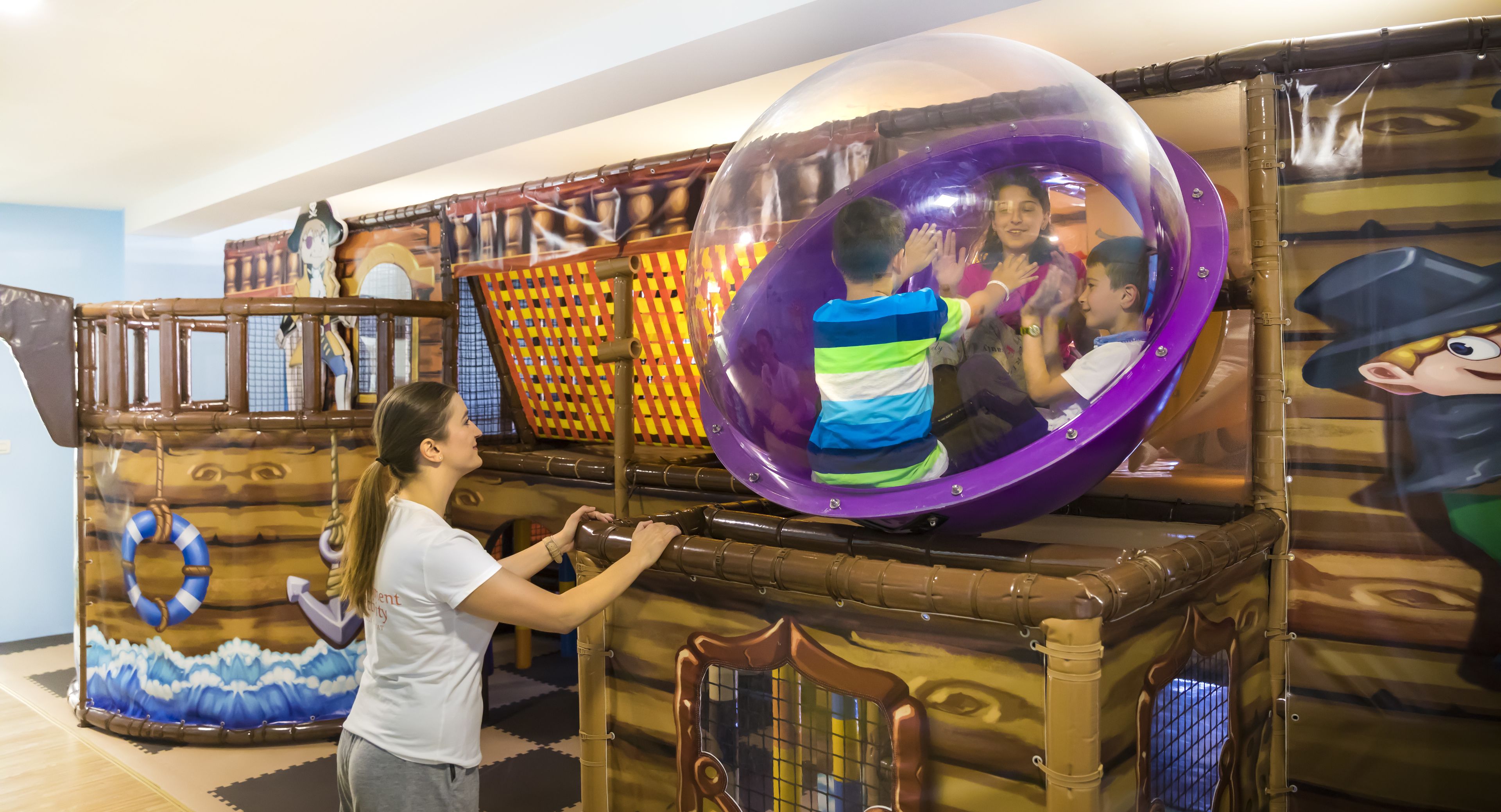 A play area with a large transparent dome and a wooden play structure.