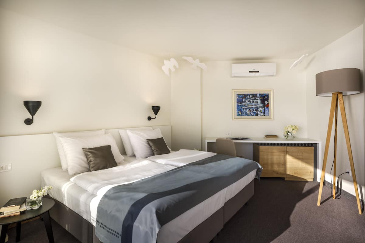Ein Hotelzimmer mit Bett, Nachttisch, Schreibtisch und Lampe.