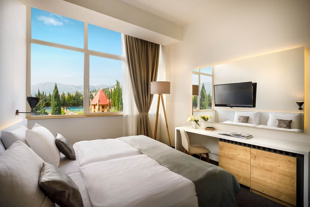 Ein Hotelzimmer mit Bett, Schreibtisch und Fernseher.