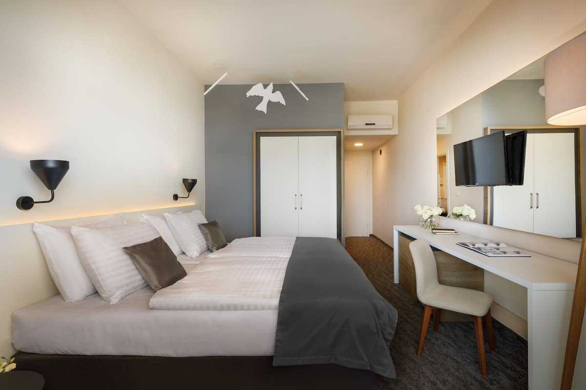 Ein Hotelzimmer mit Bett, Schreibtisch, Stuhl, Fernseher und Kleiderschrank.