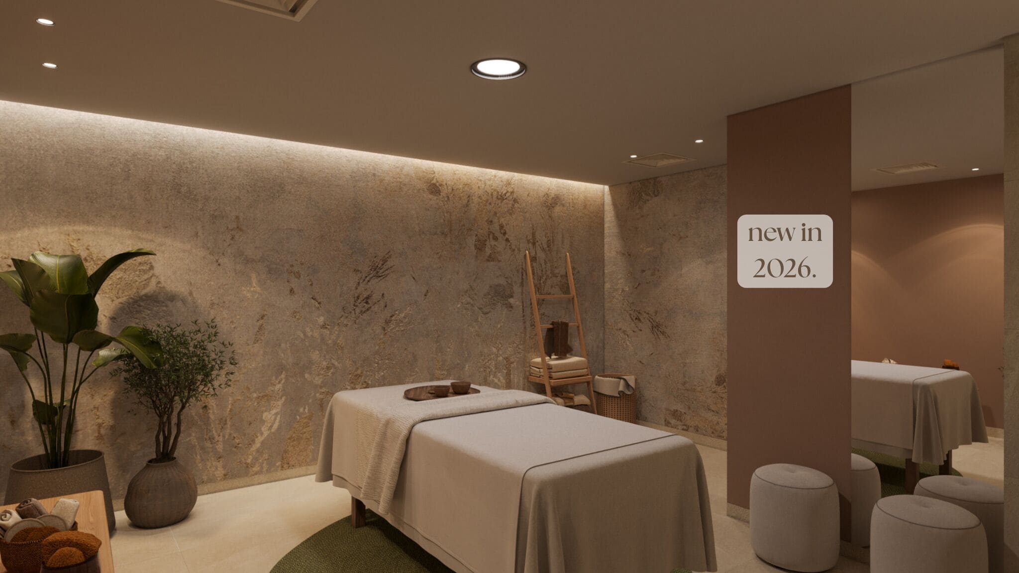 Un cuarto de spa con una mesa de masaje, una escalera de madera y un cartel que anuncia una nueva apertura en 2026.
