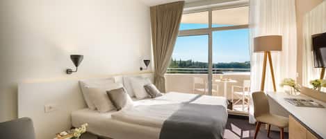 A hotel room with a bed, a desk, a chair, and a view of the outdoors.