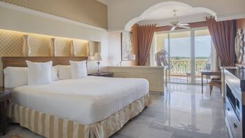 A spacious bedroom with a large bed, a balcony with a view, and a ceiling fan.