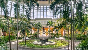 A spacious atrium with a central fountain, surrounded by lush greenery and palm trees. - JOIA Paraíso by Iberostar - Adults Only - All Inclusive (Playa del Carmen)