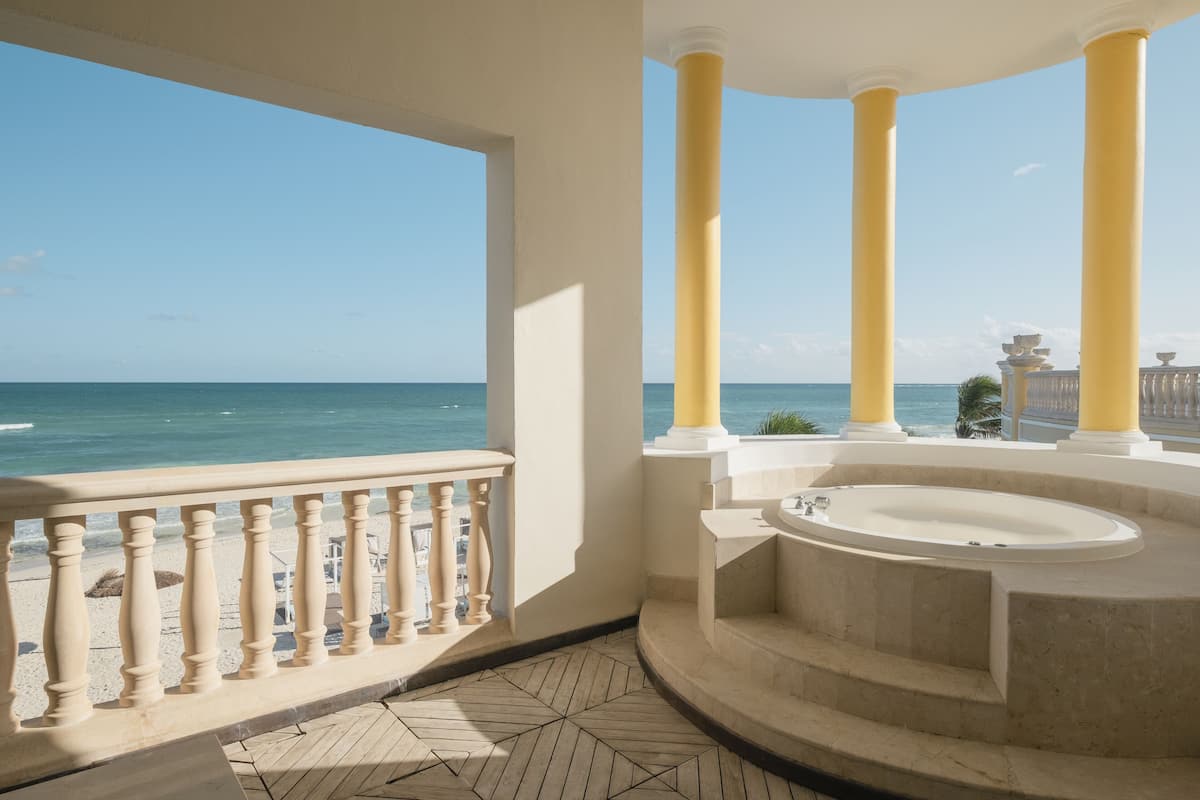 A balcony with a view of the ocean, a jacuzzi, and a balustrade.