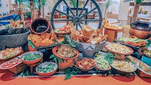 A buffet table with various dishes and a large decorative wheel in the background.