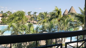 A resort with a pool, palm trees, and thatched-roof huts.