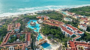 Ein Luftbild zeigt einen Resort mit mehreren Schwimmbecken, Strandhäusern und üppiger Vegetation.