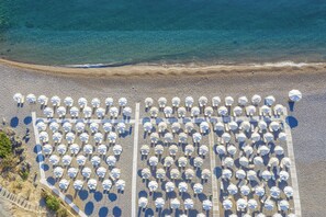 På stranden, sort sand, solsenger og parasoller