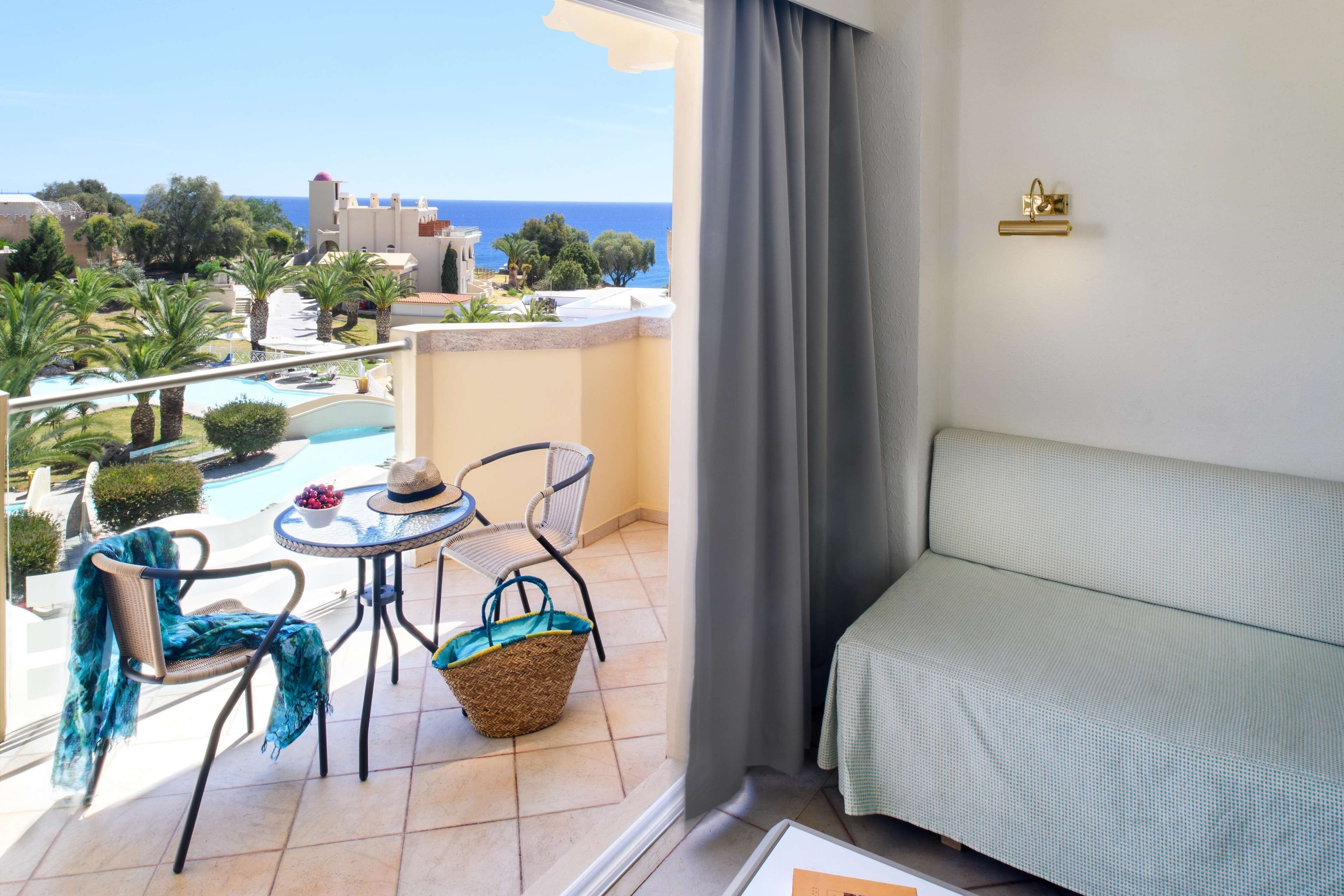 Un balcón con vista al mar, una piscina y un área de comedor con mesa y sillas.