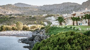A coastal resort with white buildings, palm trees, and rocky terrain.