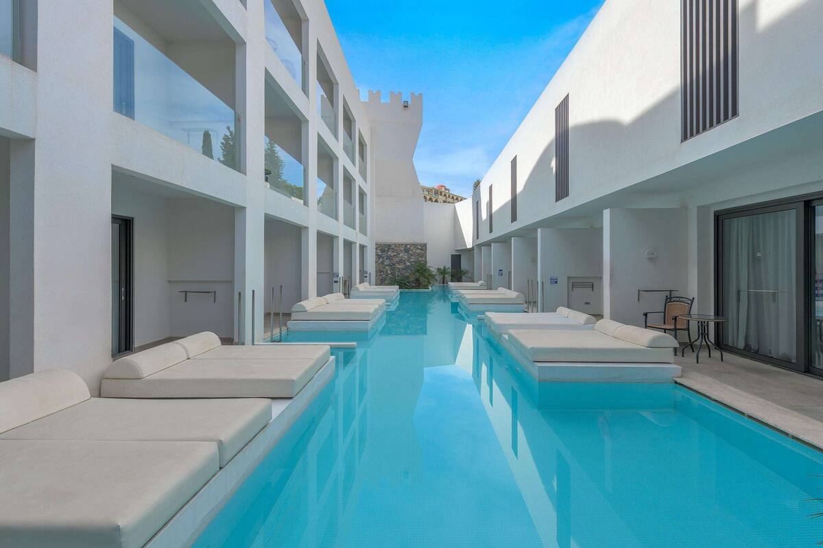 A pool area with lounge chairs and a clear view of a castle-like structure in the background.