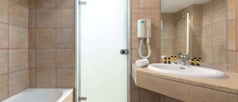 Un baño moderno con puerta de vidrio, una bañera, un lavamanos con espejo y un perchero para toallas.