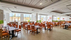 A spacious dining area with multiple tables and chairs, large windows, and a modern ceiling design. - Iberostar El Fatimi (Mahdia)