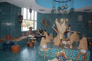 A room with patterned walls, a large window, and a central seating area with tables and chairs. - Iberostar El Fatimi (Mahdia)