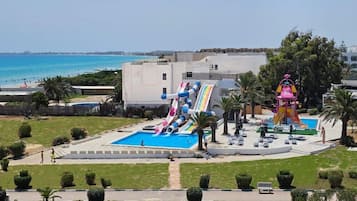 Une piscine avec un toboggan, un poste de surveillance pour les sauveteurs et une vue sur la mer.