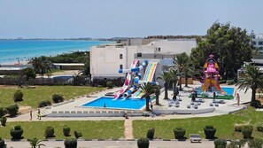 A swimming pool with a water slide, a lifeguard tower, and a view of the sea. - Iberostar El Fatimi (Mahdia)