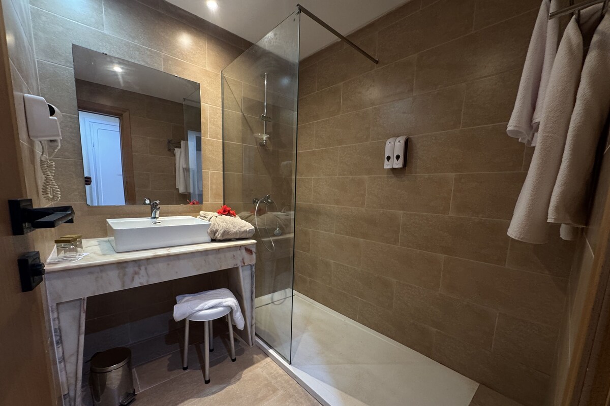 A modern bathroom with a glass-enclosed shower, a sink with a mirror, and a towel rack.