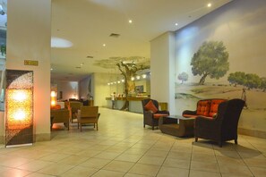 A lobby with wicker furniture, a reception desk, and a mural of a landscape. - Vincci Safira Palms (Zarzis)