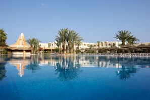 A large, clear swimming pool with palm trees and a building with arches in the background. - Iberostar Waves Mehari Djerba (Djerba Midun)