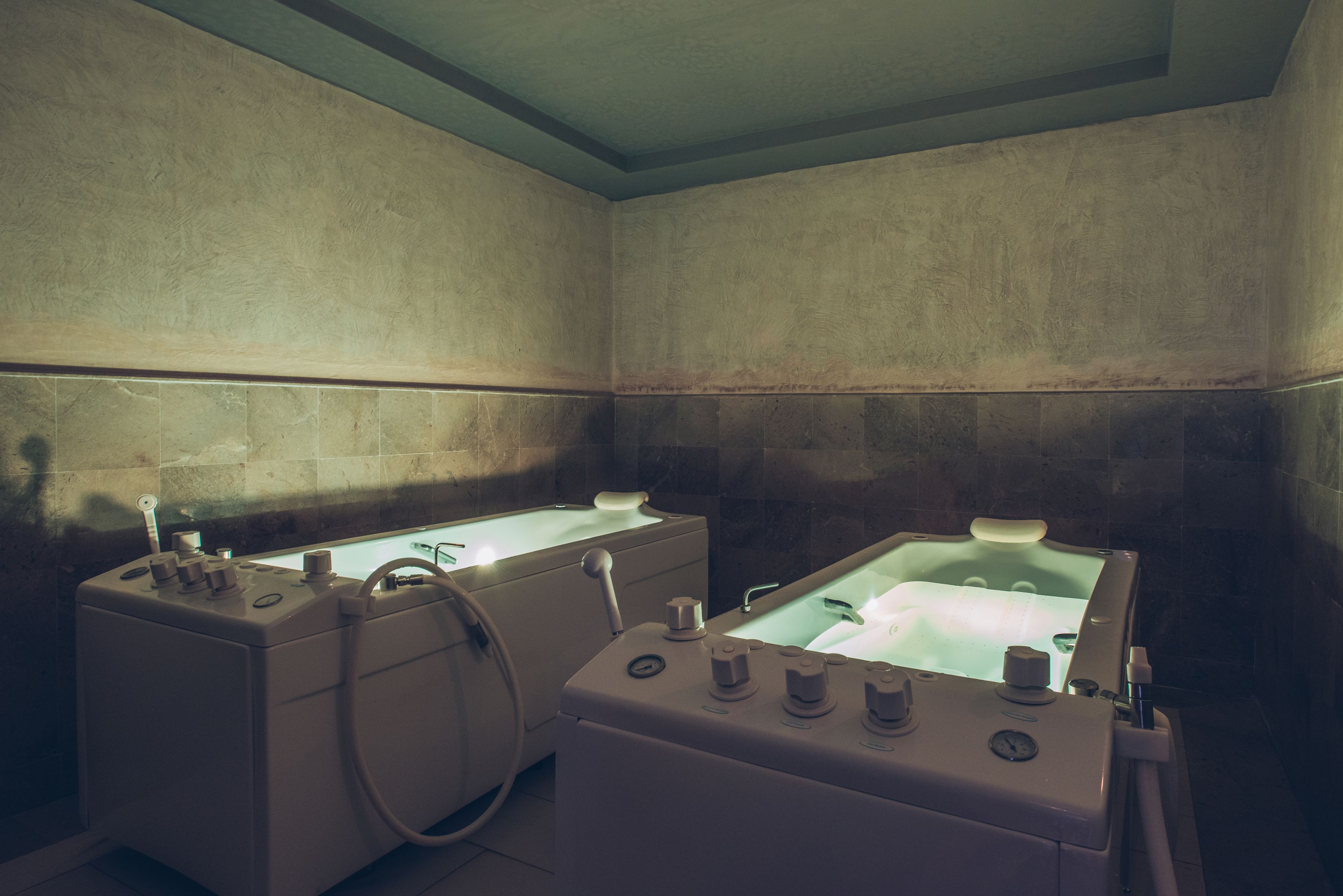 A spa room with two large tubs and a smaller massage table.