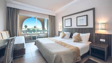 Ein Hotelzimmer mit einem großen Bett, einem Schreibtisch und einem Balkon mit Blick.