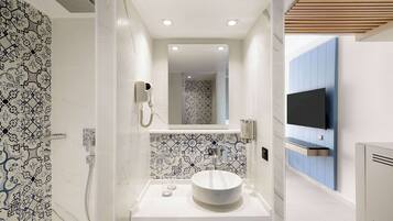 A modern bathroom with a white sink, a mirror, and a shower.