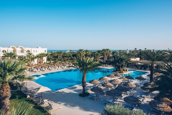 A resort with a large swimming pool, palm trees, and lounge chairs. - Iberostar Waves Mehari Djerba (Djerba Midun)