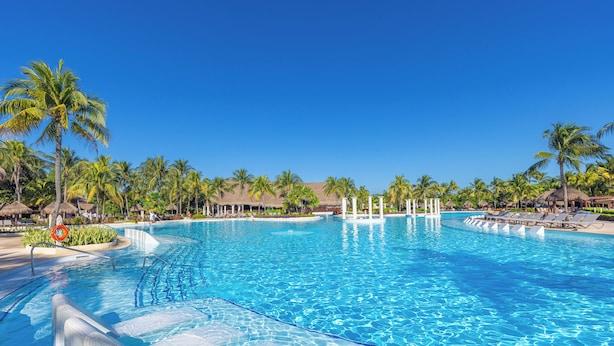A large, clear swimming pool with palm trees and lounge chairs around it. - Grand Palladium Colonial Resort & Spa All Inclusive (Kantenah)
