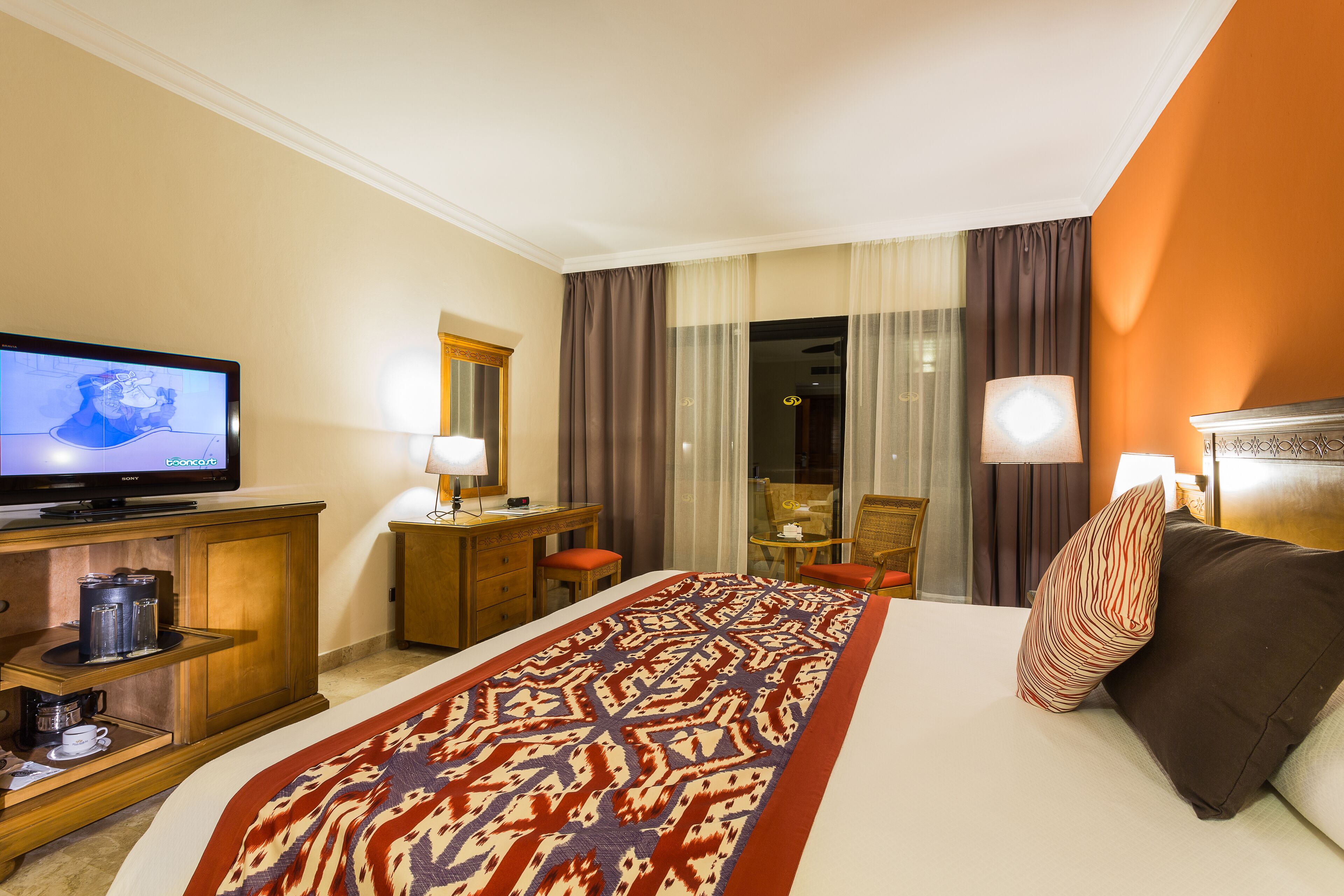 A hotel room with a bed, a TV, a desk, and a chair.